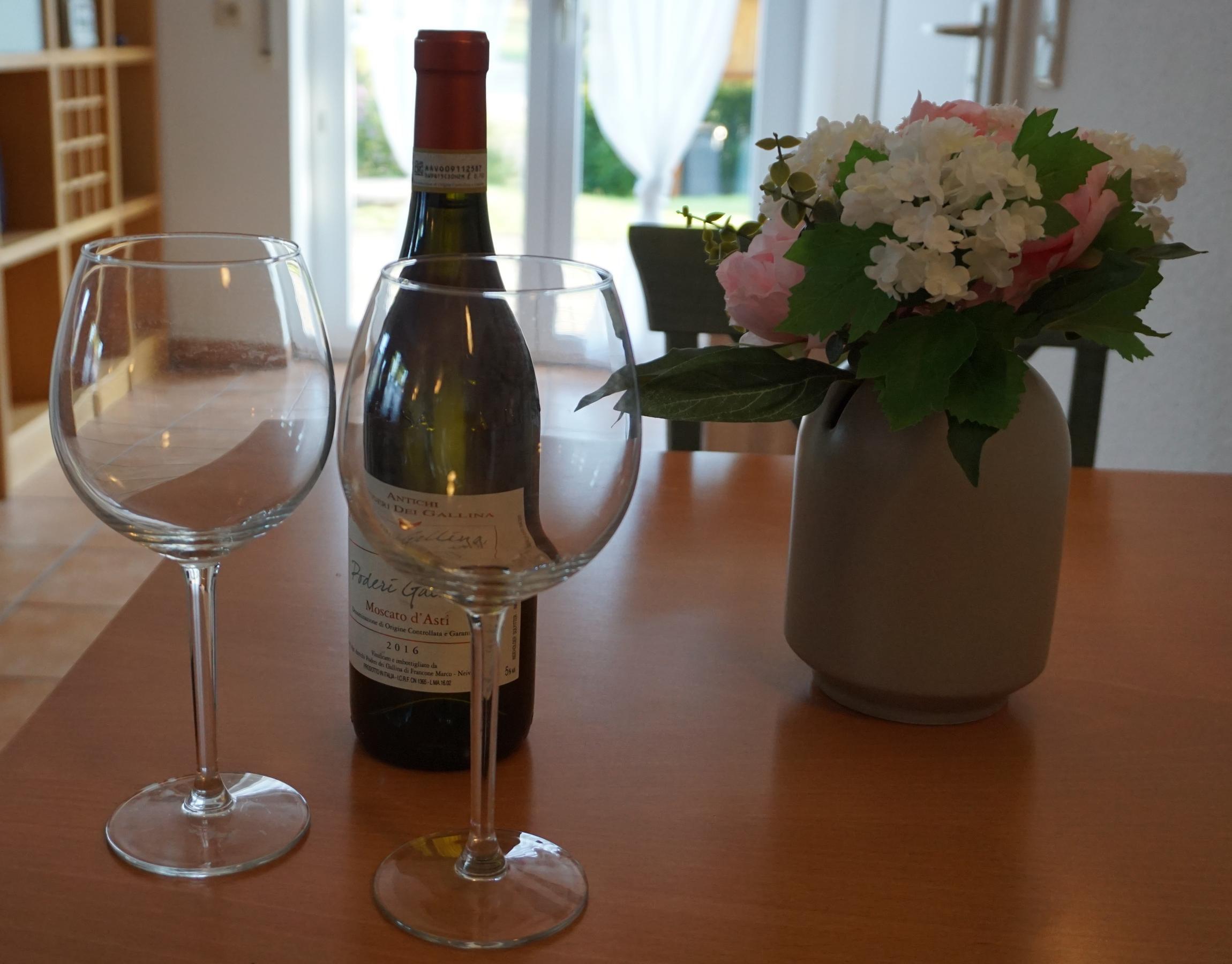 Wein mit Gläsern und Blumenstrauß
